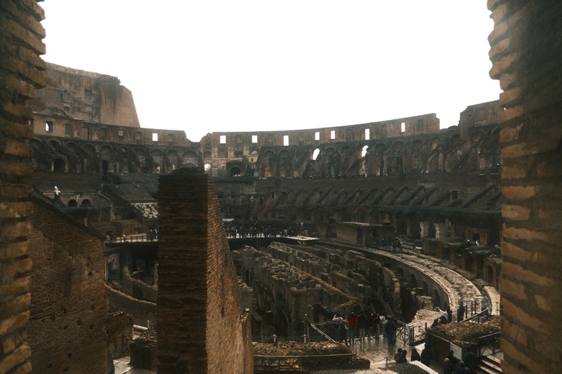 Sunlight falling across the stone arches and curved interior of the Colosseum.
