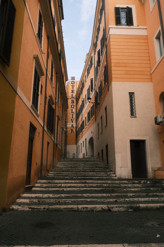 Stone steps climbing a narrow street between warm orange buildings.
