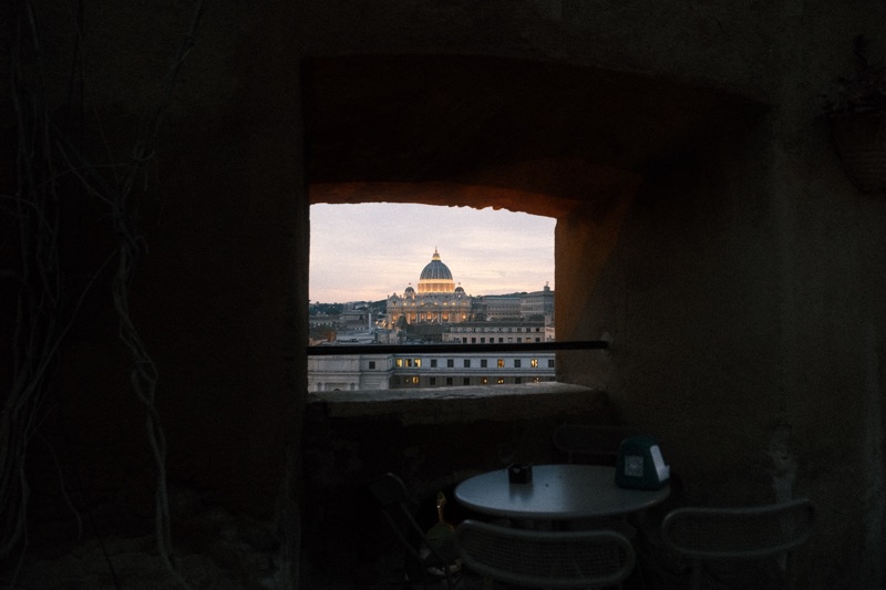 A distant illuminated dome framed by a dark stone opening above a terrace table.